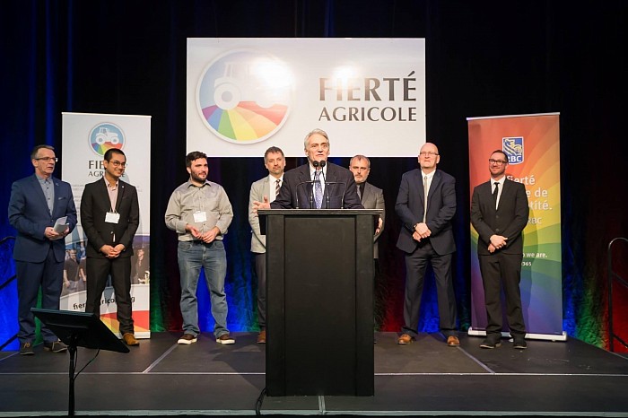 Alain Therrien (à gauche), charger de projet, et les membres du conseil d’administration (derrière) étaient fiers d’avoir organisé ce premier colloque sur les réalités LGBTQ+ en milieu agricole et rurale, présenté par un animateur exceptionnel Errol Duchaine.